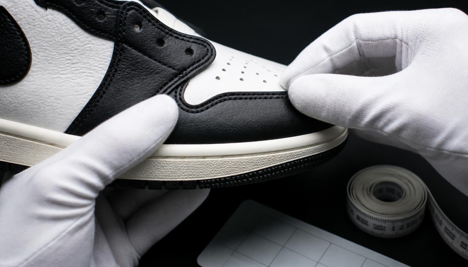 Gloved hands inspecting the stitching and midsole of a sneaker under studio light